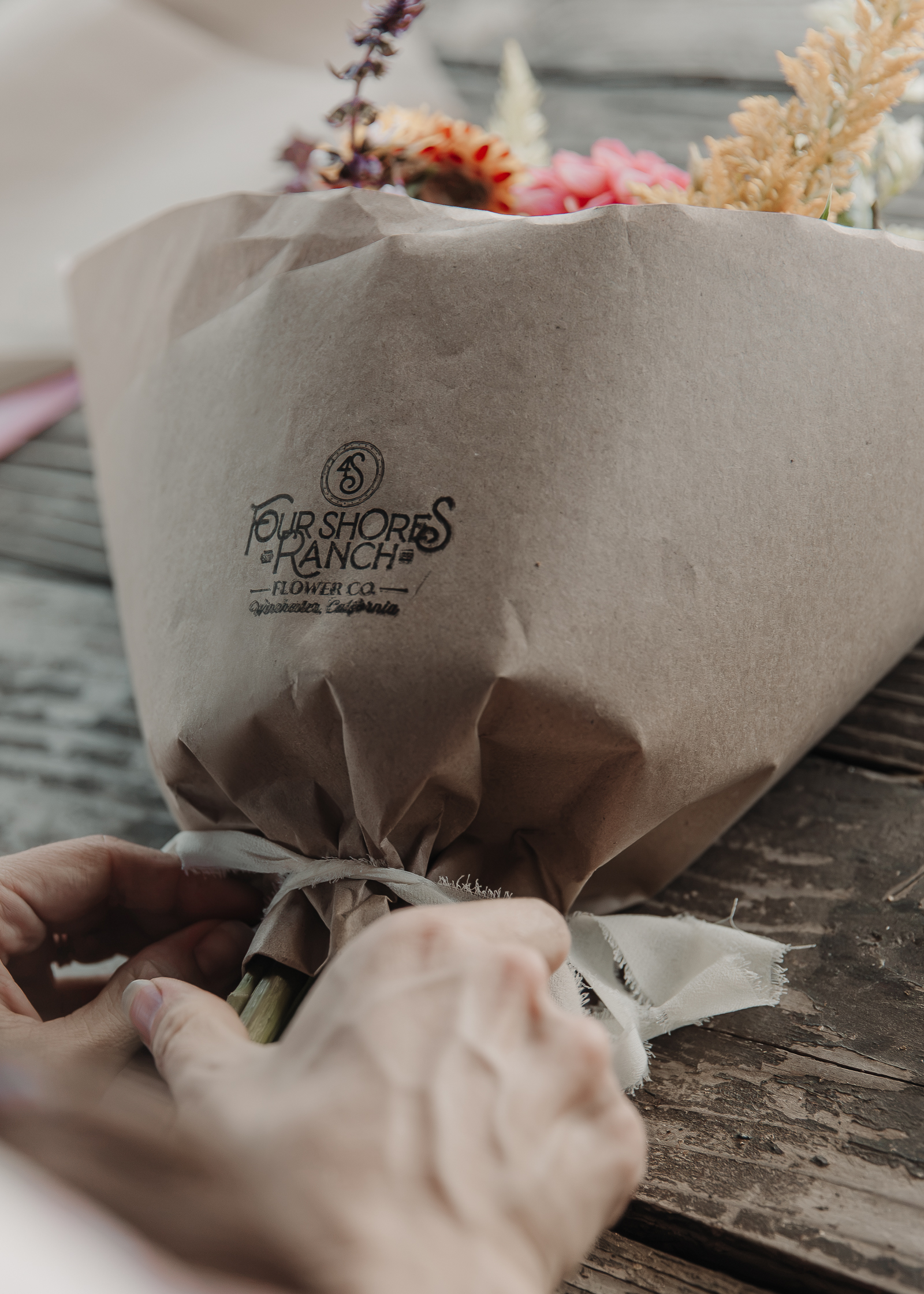 Tying off a bouquet wrapped with the Four Shores Ranch stamp